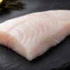 Fresh raw white sea bass fillet on dark slate with lemon